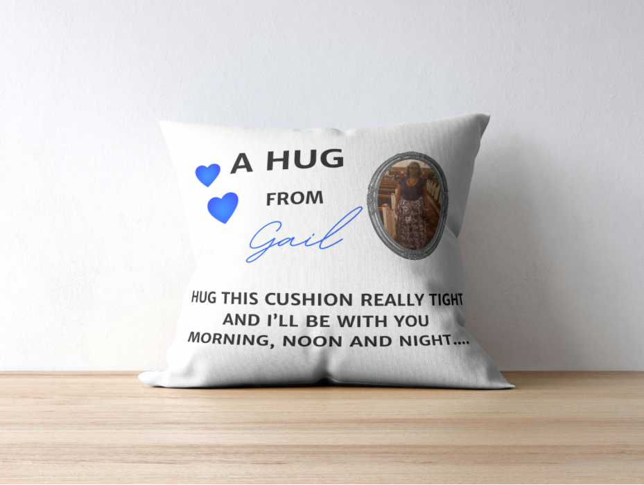 A rectangular pillow with 'A Hug' text and a blue heart symbol on it, personalized with a name and a memorial picture.